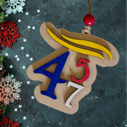 Trump Christmas ornament with numbers 45 and 47 on a wood background painted red white and blue.